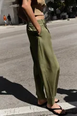 Pantalón de tiro alto con corte recto, bolsillos delanteros y detalle de pinzas con botones en la cintura. Cuenta con cierre frontal de cremallera y gancho metálico.