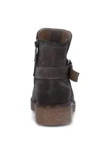 Bota corta de descarne color gris, con diseño de caña baja y detalle de tira con hebilla metálica lateral. Cuenta con suela de goma texturizada y cierre lateral para un ajuste cómodo.