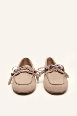 Mocasín estilo náutico de gamuza marrón, con cordones de cuero, borla decorativa y cuentas de colores en el empeine.
