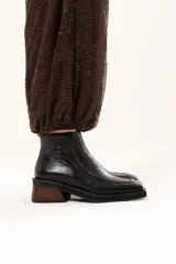 Bota de cuero color chocolate con horma cuadrada, taco bloque de madera y plataforma. Presenta cierre lateral interno y detalle de ribete en la capellada.