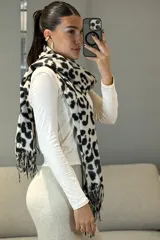 Bufanda rectangular con estampado animal print en tonos blanco y negro, con terminaciones de flecos en los extremos.