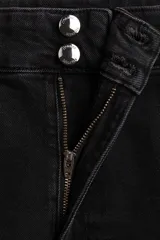 Jean de denim de algodón con leve stretch, de tiro alto y corte wide leg. Presenta cierre frontal con doble botón, bolsillos traseros de parche y pliegues marcados en la parte delantera y trasera.