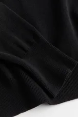 Polera negra de punto fino suave, con cuello alto, manga larga y bajo recto. Cuello, puños y bajo acanalados.