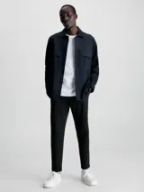 Camisa negra de popelina con corte relaxed, cierre frontal con botones, mangas largas y dos bolsillos con solapa en el pecho.