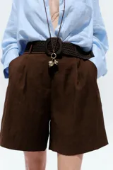 Bermuda de tiro alto color azul marino, con pinzas delanteras, bolsillos laterales y cinturón trenzado color marrón.