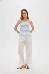 Top de algodón con diseño estampado de cuadros vichy en tonos celeste y blanco, corte al cuerpo con escote recto y tirantes finos. Presenta cuerpo fruncido tipo smock con cordones ajustables en los laterales que forman un pequeño volado en el ruedo.