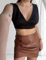 Minifalda marrón de cuero sintético con frunces laterales y corte cruzado.