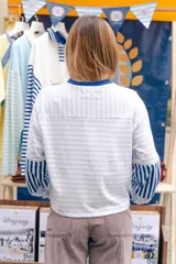 Remera de manga larga con corte boxy, confeccionada en algodón. Presenta un diseño a rayas horizontales celestes y blancas, con puños en contraste azul oscuro, tajos laterales y logo bordado en el pecho.