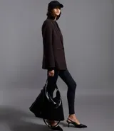 Blazer de sastrería en color negro, de corte alargado y estructura recta. Presenta solapas clásicas, cierre frontal con dos botones, hombros estructurados y mangas largas con detalle de botones en los puños. Incluye bolsillos decorativos y forro interno.