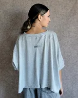 Remera de corte oversize y estilo crop, confeccionada en lanilla de textura suave. Presenta cuello redondo y mangas cortas con caída holgada.