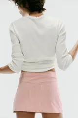 Falda mini de tiro bajo color rosado con estampado de rayas verticales. Presenta dos bolsillos de parche en el frente con detalles de cordones cruzados ajustables y cierre lateral con cremallera oculta.