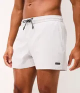 Bermuda de running Get Over para hombre, confeccionada en microfibra ligera de color gris claro. Presenta cintura elástica con cordón ajustable, bolsillos funcionales, dobladillo redondeado con aberturas laterales y pequeño parche con logo de la marca en la pierna izquierda.