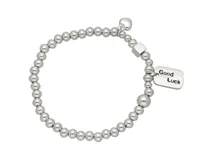 Pulsera elástica de acero plateado con bolitas y dije rectangular con la inscripción "Good Luck".