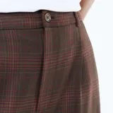 Pantalón marrón de corte ancho y talle alto, con estampado a cuadros y pinzas en la parte delantera.