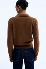 Cárdigan corto de tejido de punto suave, color marrón oscuro, con cuello camisero, abotonadura frontal y remates acanalados en puños y bajo.