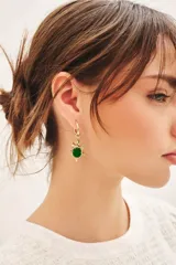 Aro colgante dorado con forma de tortuga y una piedra de resina verde en el centro.