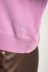 Buzo lila oversize confeccionado en 100% algodón, con cuello redondo, mangas largas y puños y dobladillo acanalados. Presenta un pequeño detalle bordado en el bajo.