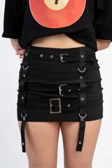 Minifalda negra con tres hileras de correas ajustables con hebillas plateadas.