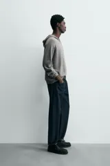 Jersey de lana gris, corte regular, con cuello pico que incorpora una capucha y manga larga. Presenta acabados en rib en puños y bajo.