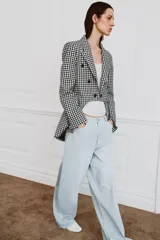 Blazer Zara Woman Collection de corte asimétrico con estampado de cuadros vichy en blanco y negro. Presenta cuello solapa, cierre frontal con botones y un diseño de bajo irregular con abertura central.