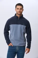 Buzo térmico de polar con diseño bicolor en azul marino y beige. Presenta cuello alto con medio cierre frontal, mangas largas y bolsillos laterales con cierre.