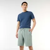 Bermuda de felpa ligera color verde suave, con cintura elástica y bolsillos laterales, de corte cómodo y diseño liso.
