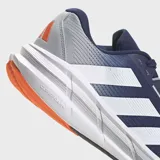 Championes de running Adidas Questar 3 para hombre, color azul marino con tres franjas blancas en el lateral. Presentan detalles en gris claro en el talón y toques naranjas en la suela. La mediasuela es blanca con tecnología Bounce 2.0 y plantilla Cloudfoam Plus.