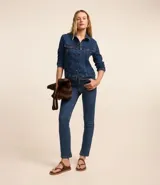 Pantalón de jean azul, corte slim, con trabillas en la cintura, bolsillos, cierre delantero tradicional y abertura en el bajo.