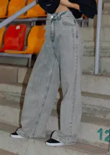 Jean de corte oversize con tiro medio-alto, confeccionado en denim de algodón con lavado tipo ice wash en tono grisáceo. Presenta diseño de cinco bolsillos, cierre frontal y etiqueta de cuero en la parte posterior de la cintura.