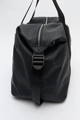 Bolso tipo duffel negro de símil cuero con cierre superior de cremallera metálica y asas reforzadas.