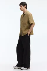 Camisa de manga corta H&M con cuello resort, cierre frontal de botones y bolsillos frontales aplicados. Confeccionada en tejido texturizado de corte relajado.