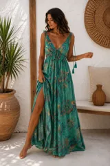 Vestido largo verde con estampado abstracto en tonos dorados y marrones, escote en V con cordones ajustables terminados en borlas, tiritas para atar en los hombros y tajo frontal en la falda.