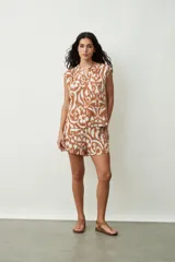 Blusa negra sin mangas, con cuello mao y abertura frontal con botones. Presenta frunces en la zona de los hombros, dándole un calce holgado.