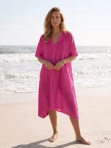 Vestido estilo túnica color fucsia de lino, con escote en V, manga corta, bolsillos laterales y diseño asimétrico más largo en la parte trasera.