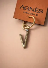 Aro tipo argolla con dije colgante en forma de letra, fabricado en bronce. Se vende por unidad.