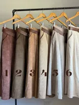 Falda midi de corte clásico confeccionada en corderoy, con cintura elastizada, diseño de tablas y bolsillos laterales. Incluye un cinturón desmontable en color marrón.