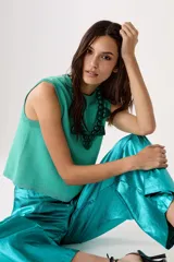 Top tejido de punto color turquesa con lúrex, sin mangas y cuello a la base.