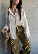 Camisa de manga larga color marfil con detalles de encaje y botones frontales.