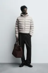 Campera puffer acolchada de corte regular fit en color negro, confeccionada en tejido técnico repelente al agua. Presenta cuello subido con capucha, cierre frontal de cremallera, mangas largas con puños elásticos y bolsillos laterales de vivo.