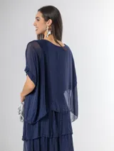 Vestido largo azul marino de seda italiana, con diseño de volados escalonados en la falda y una sobrecapa superior con mangas cortas amplias.