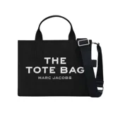 Bolso tote de lona color negro con estampado frontal en blanco que reza 'THE TOTE BAG MARC JACOBS'. Cuenta con doble asa superior, cierre de cremallera y correa larga ajustable y extraíble.