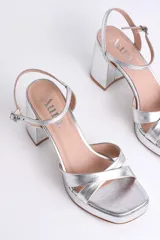 Sandalias negras de cuero sintético con plataforma y tacón cuadrado. Presentan tiras cruzadas en el empeine y pulsera con hebilla al tobillo.