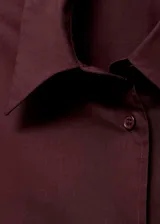 Camisa oversize de popelín de algodón en color bordó, de manga larga con puños abotonados, cuello camisero y cierre delantero con botones.