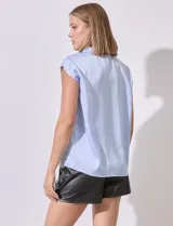 Camisa celeste de satén sin mangas, con cuello con solapa y abertura central con botones.