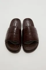 Sandalias planas color marfil, con tira ancha acolchada en el empeine y suela baja con borde oscuro.