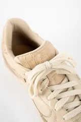 Zapatilla de cuero legítimo en tonos beige, con diseño combinado que incluye paneles de cuero liso, cuero con textura de reptil y detalles de gamuza en la puntera y el talón. Cuenta con cordones al tono y suela de goma.