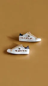 Championes de cuero color blanco y marfil, con detalles pintados a mano por Carolina De Cunto, apliques en tono dorado, talón negro y suela de goma.