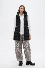 Chaleco acolchado negro con capucha ajustable mediante cordones, cierre frontal con botones a presión y bolsillos laterales con cierre.