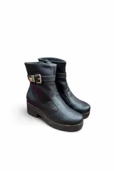 Bota corta de cuero color marrón con suela track y taco bloque. Incluye una tira decorativa en el tobillo con hebilla metálica dorada.