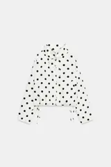 Chaqueta blanca con estampado de lunares negros, cuello subido ajustable con cordón, cierre frontal con botones y bajo ajustable con cordones.